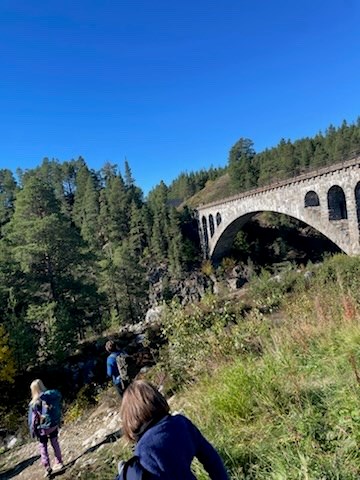 En gruppe mennesker som går på en sti nær en steinbro