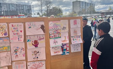 en gruppe mennesker som står ved siden av en vegg med plakater på