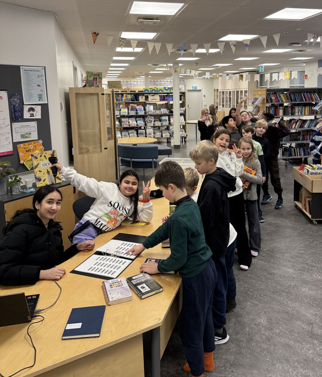 en gruppe mennesker som står rundt et bord med bøker på en gruppe mennesker som står rundt et bord med bøker på