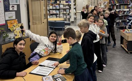 en gruppe mennesker som står rundt et bord med bøker på en gruppe mennesker som står rundt et bord med bøker på