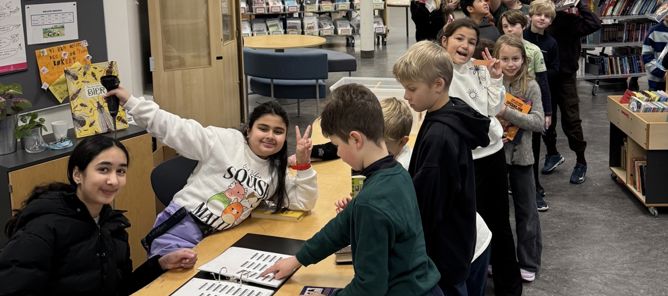 en gruppe mennesker som står rundt et bord med bøker på en gruppe mennesker som står rundt et bord med bøker på