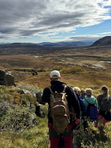 en gruppe mennesker som står på en høyde med en vannmasse i bakgrunnen