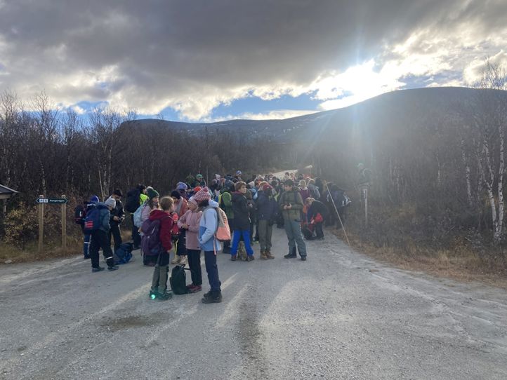 en gruppe mennesker som står på en vei med et fjell i bakgrunnen en gruppe mennesker som står på en vei med et fjell i bakgrunnen